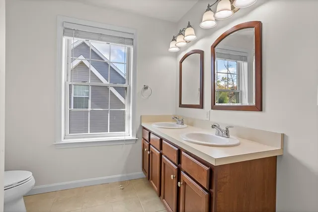 a bathroom with a double vanity sink a toilet and a mirror