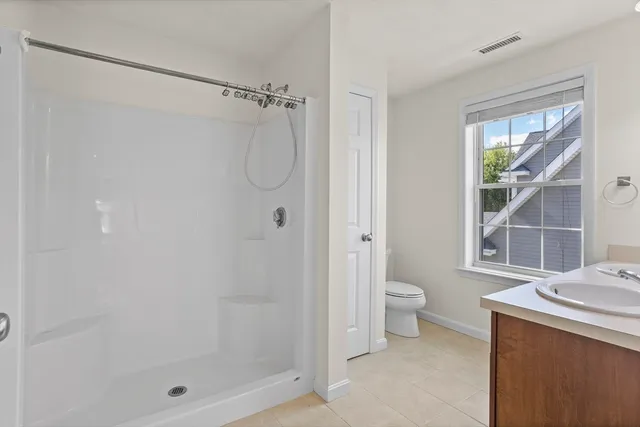 a bathroom with a granite countertop shower a mirror and a toilet