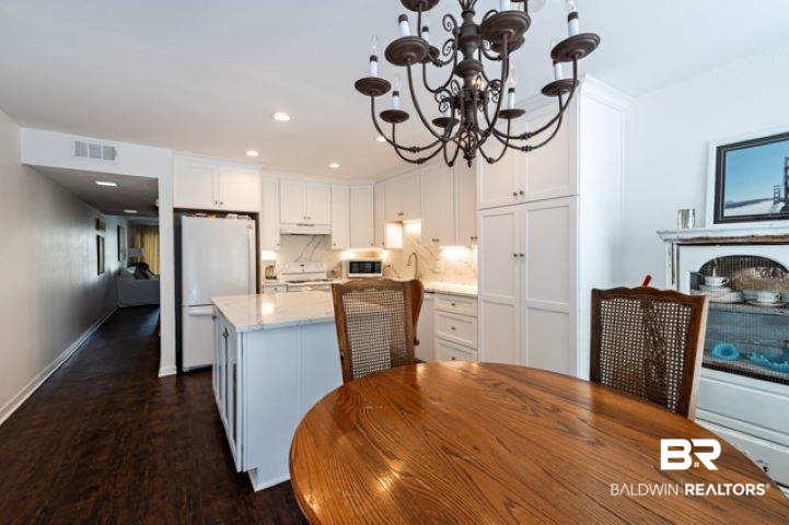 710 South Mobile Street, Unit 52 Fairhope, AL 36532 - Photo 8 of 58 Kitchen featuring freestanding refrigerator, a chandelier, white cabinets, dark wood finished floors, and backsplash