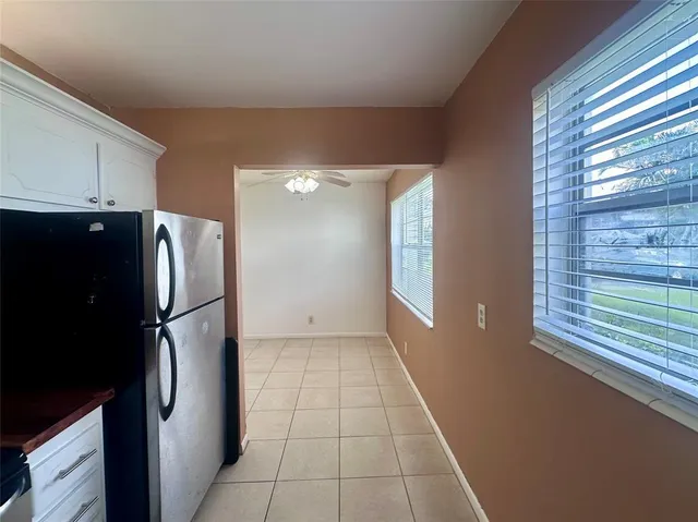 a view of a refrigerator in kitchen and an empty room