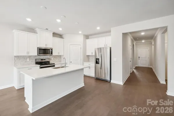 a kitchen with stainless steel appliances granite countertop a refrigerator oven a sink with white countertops and wooden floor