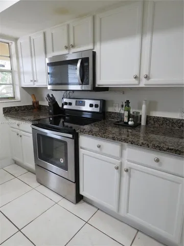a kitchen with granite countertop white cabinets and appliances
