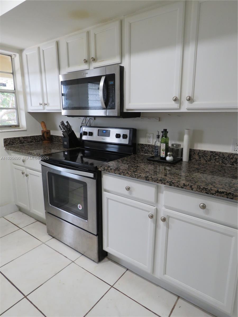 11840 Northeast 19th Drive, Unit 26 North Miami, FL 33181 - Photo 6 of 15 a kitchen with granite countertop white cabinets and appliances