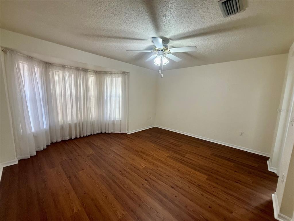 8037 Southwest 115th Loop Ocala, FL 34481 - Photo 23 of 47 an empty room with wooden floor fan and windows