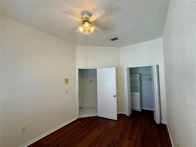 an empty room with wooden floor and a ceiling fan