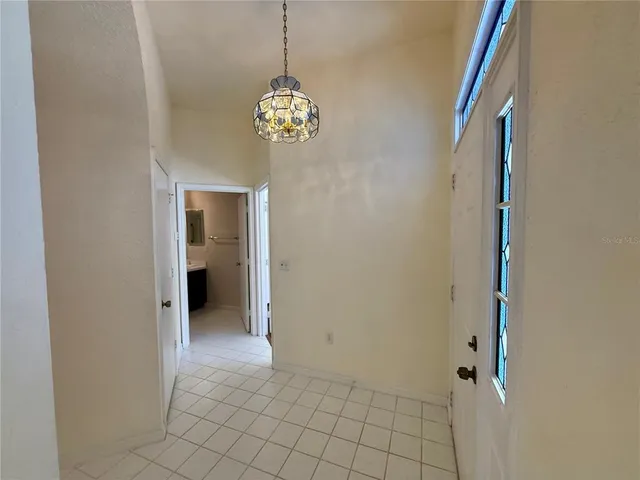 a view of a hallway with chandelier and glass door