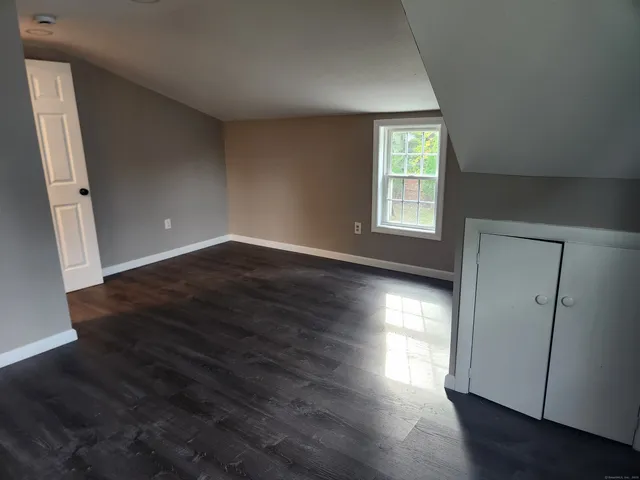 an empty room with wooden floor and windows with curtains