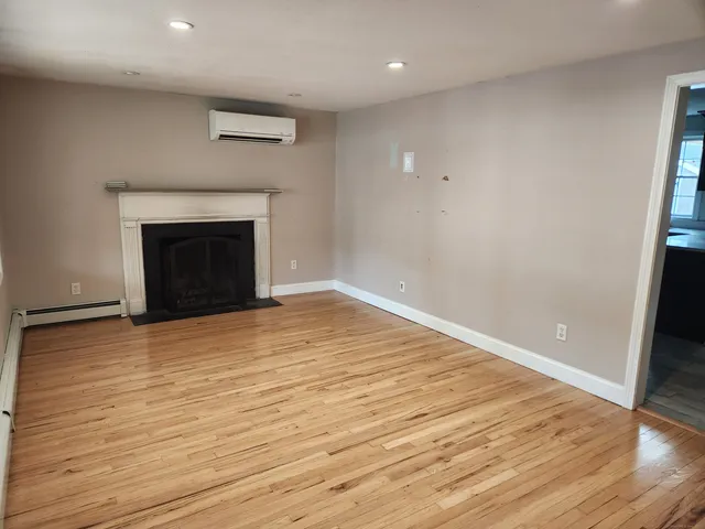 a view of empty room with wooden floor and fireplace