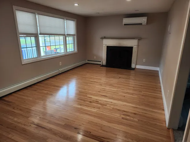an empty room with wooden floor fireplace and windows