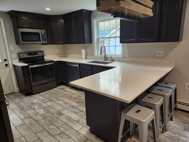 a kitchen with stainless steel appliances wooden cabinets a stove a sink and a microwave