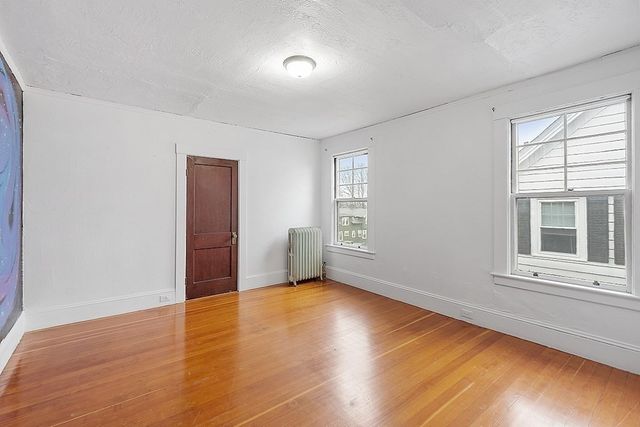 a view of an empty room with wooden floor and stairs