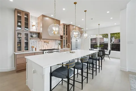 a kitchen with stainless steel appliances granite countertop a sink a stove a refrigerator and island with wooden floor