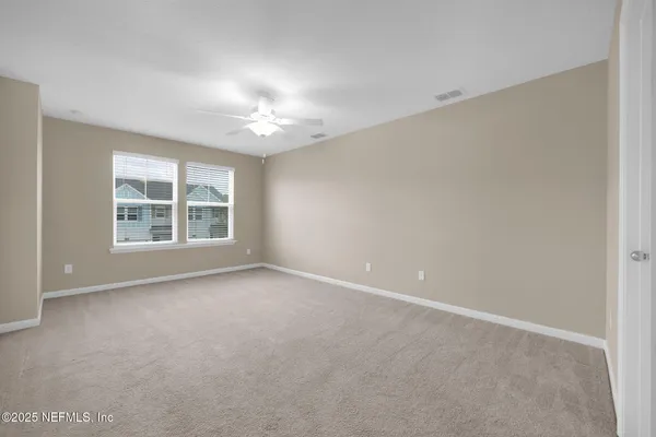 an empty room with windows and ceiling fan