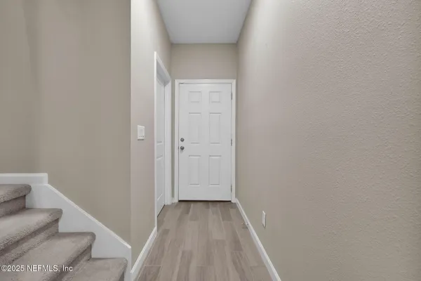 a view of a hallway with wooden floor and furniture