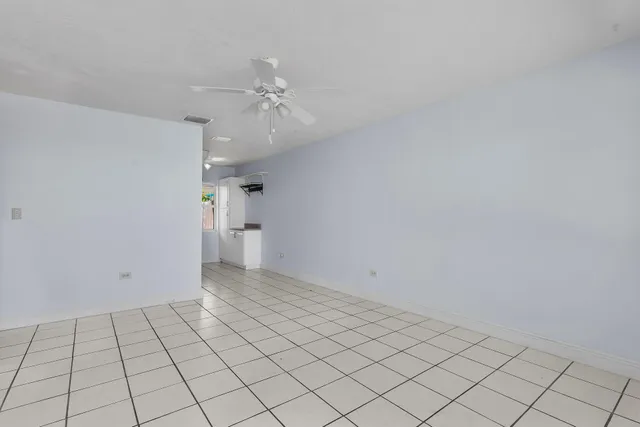 an empty room with white walls and chandelier fan