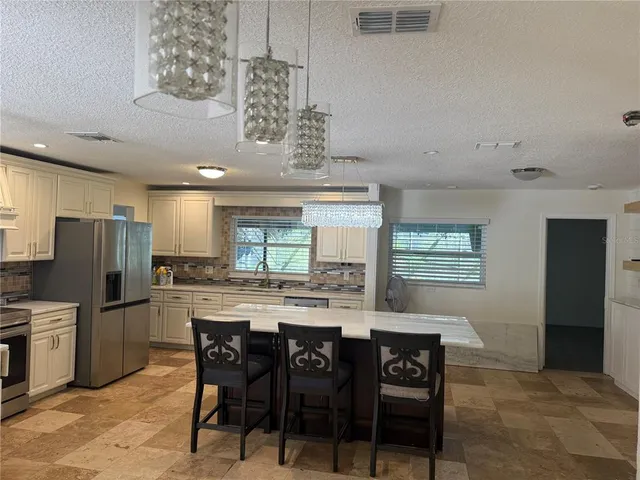 a kitchen with stainless steel appliances a dining table chairs and refrigerator