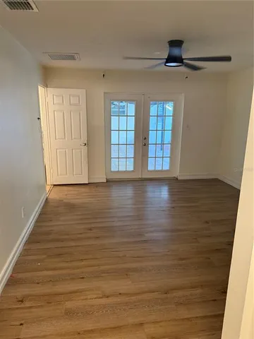 a view of an empty room with window and wooden floor