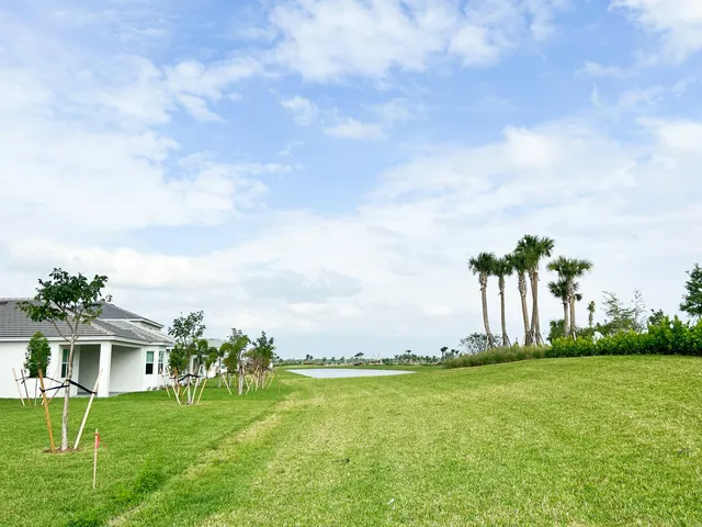 a view of a white house with a big yard and potted plants