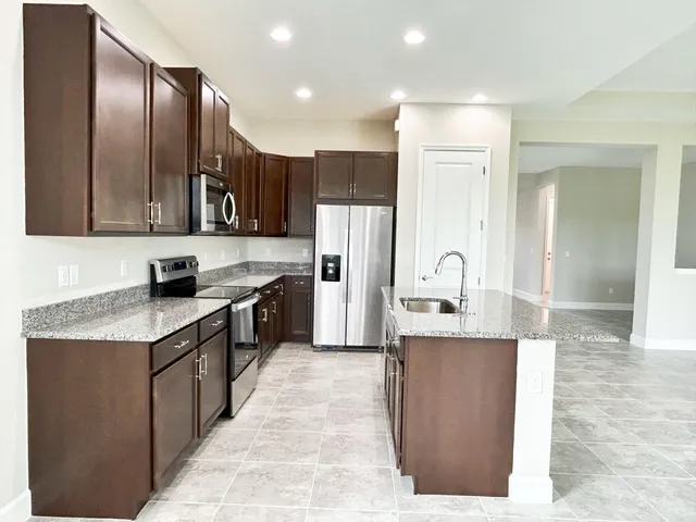 a large kitchen with stainless steel appliances kitchen island granite countertop a refrigerator and a stove top oven