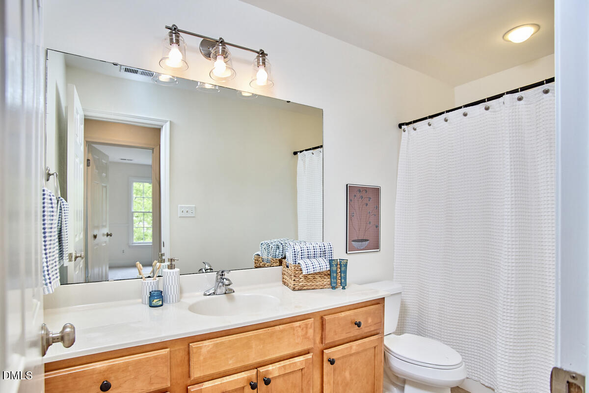 8030 Sundance Circle Durham, NC 27713 - Photo 36 of 61 a bathroom with a sink a toilet a mirror and shower curtain