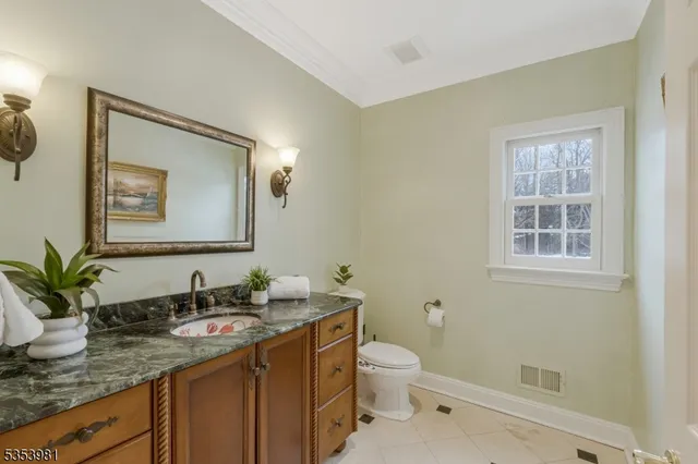 a bathroom with a granite countertop sink toilet and mirror