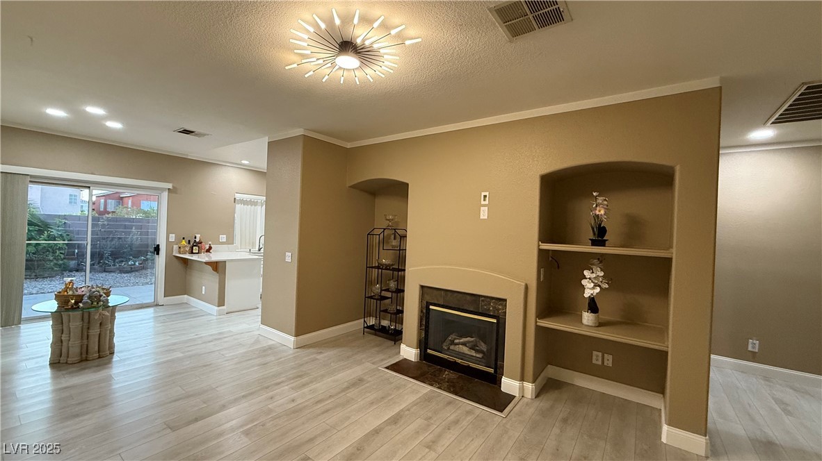 7062 Russell Ranch Avenue Las Vegas, NV 89113 - Photo 12 of 32 Living room with arched walkways, a tile fireplace, visible vents, and wood finished floors