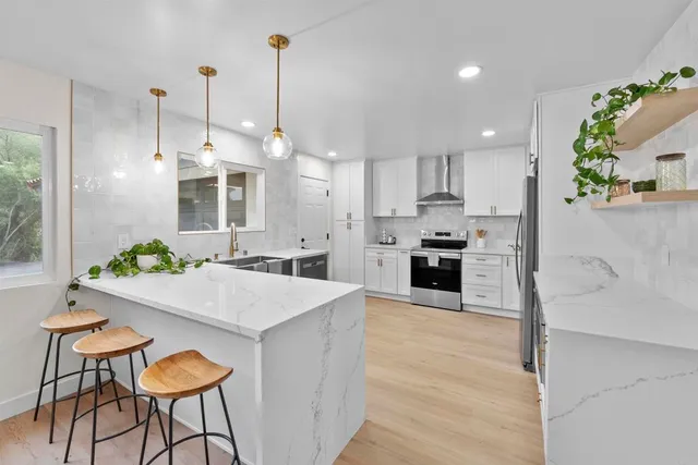 a kitchen with stainless steel appliances kitchen island granite countertop a table chairs and a living room