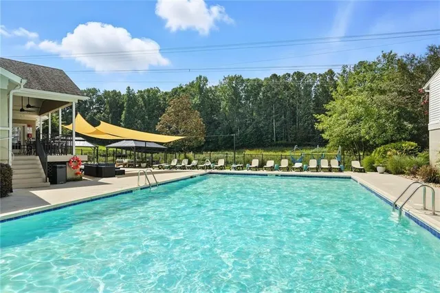 a view of a swimming pool with lawn chairs and a big yard