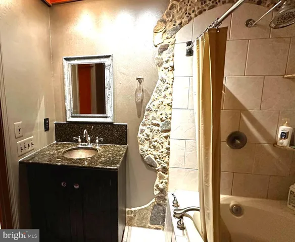 a bathroom with a granite countertop shower a sink and a mirror