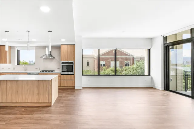 a large kitchen with kitchen island a large window a sink and stainless steel appliances
