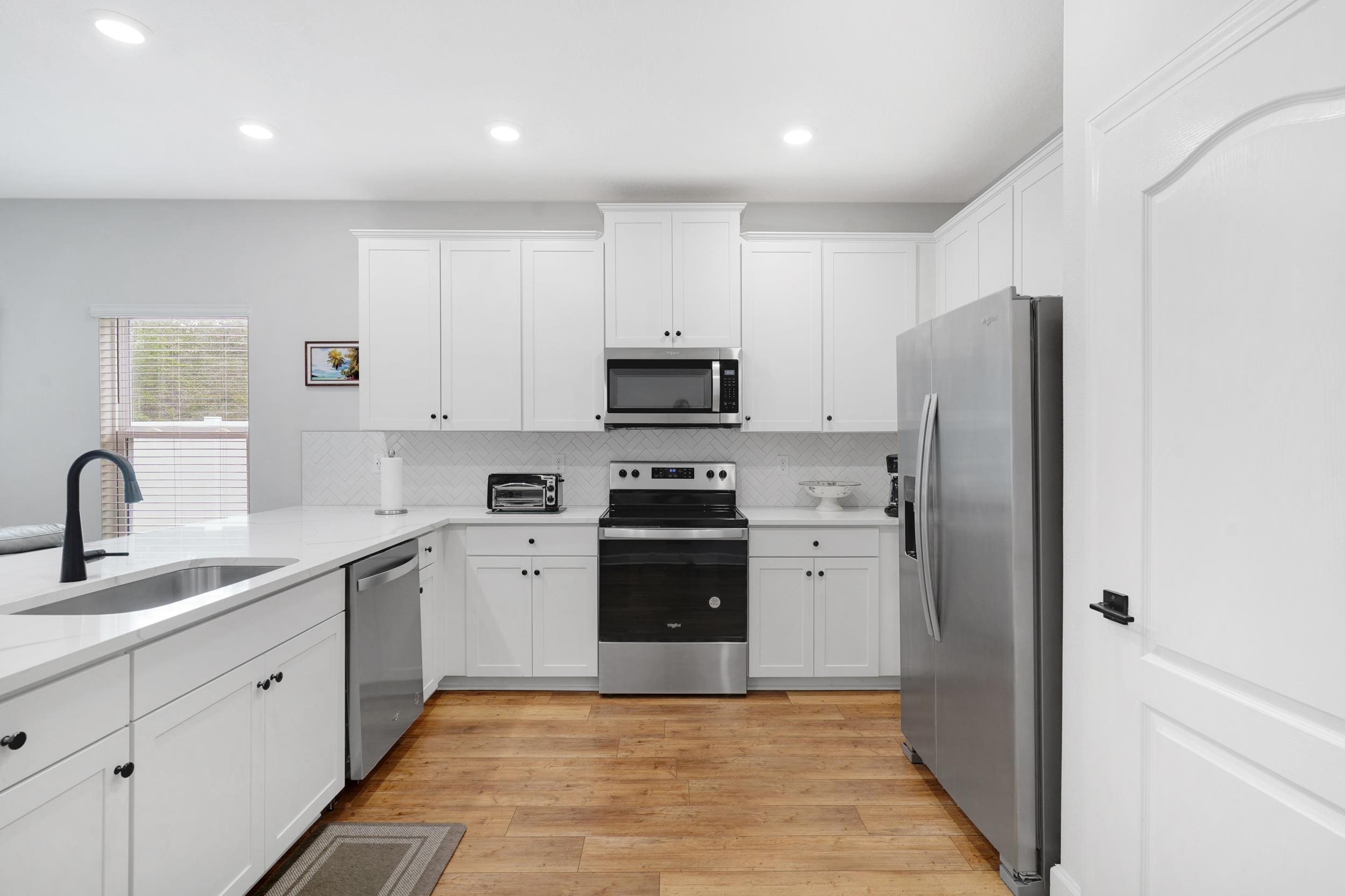 1014 Morgans Treasure Road St. Augustine, FL 32084 - Photo 6 of 31 a kitchen with white cabinets and stainless steel appliances