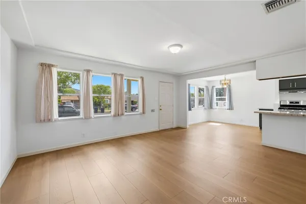 a view of an empty room with a window and wooden floor