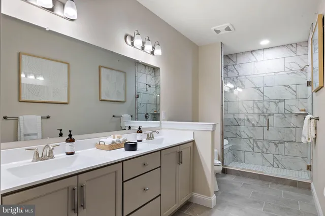 a bathroom with a double vanity sink a shower and a mirror