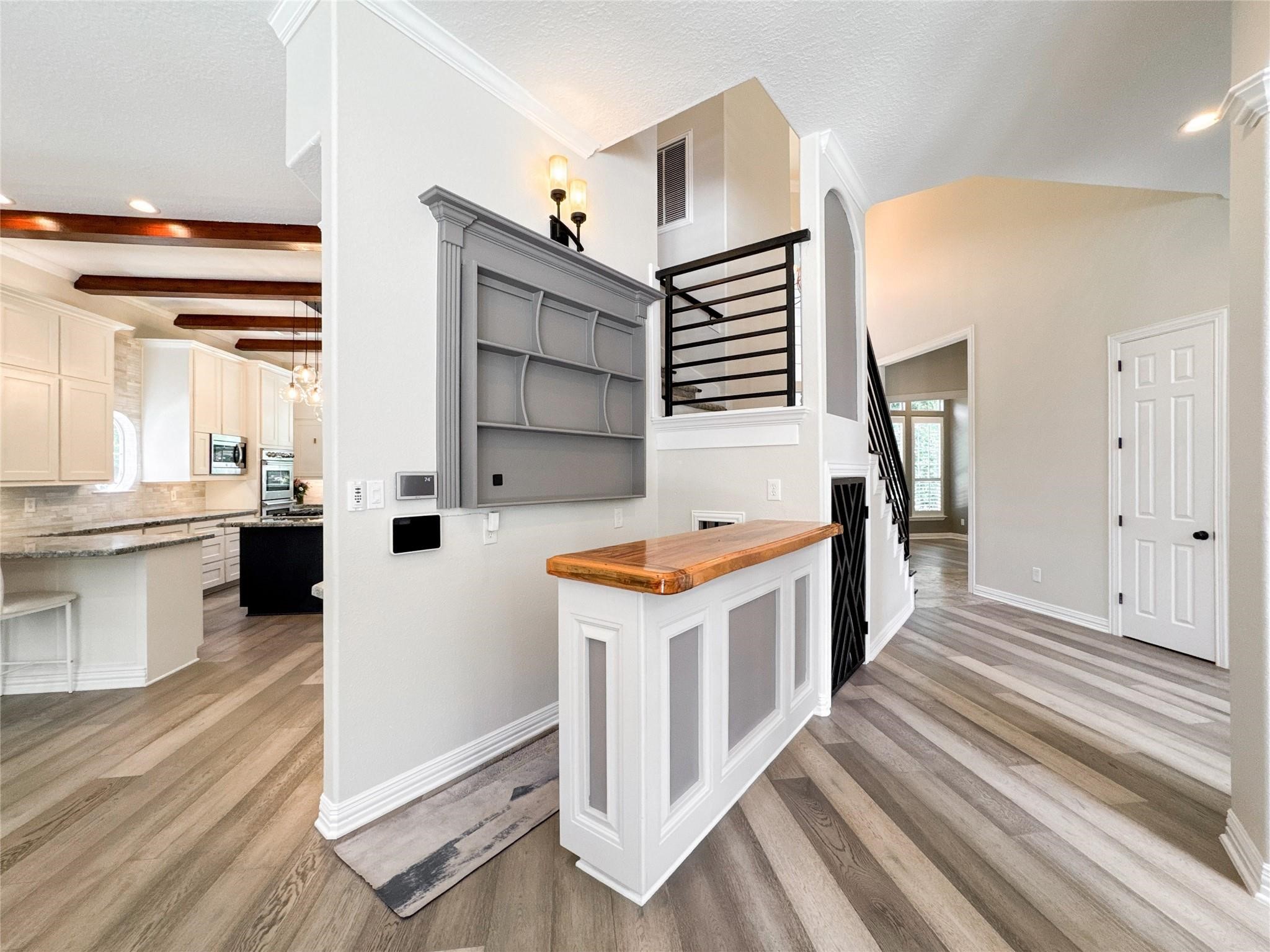 1810 Woerner Road Houston, TX 77090 - Photo 13 of 39 This home features a bright, open entryway with modern flooring and a stylish staircase. The kitchen, visible to the left, offers ample cabinetry, sleek countertops, and exposed wooden beams, creating a warm and welcoming atmosphere.