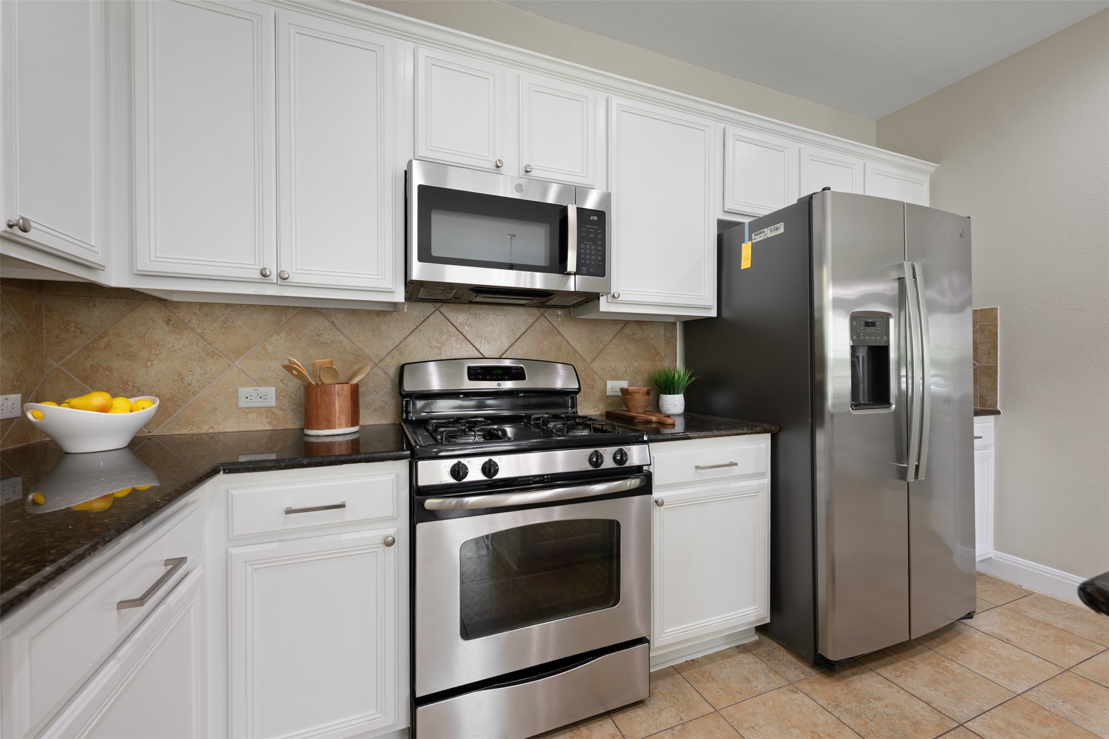 18820 Edinburgh Castle Road Pflugerville, TX 78660 - Photo 13 of 37 a kitchen with stainless steel appliances white cabinets white stove a microwave and a refrigerator