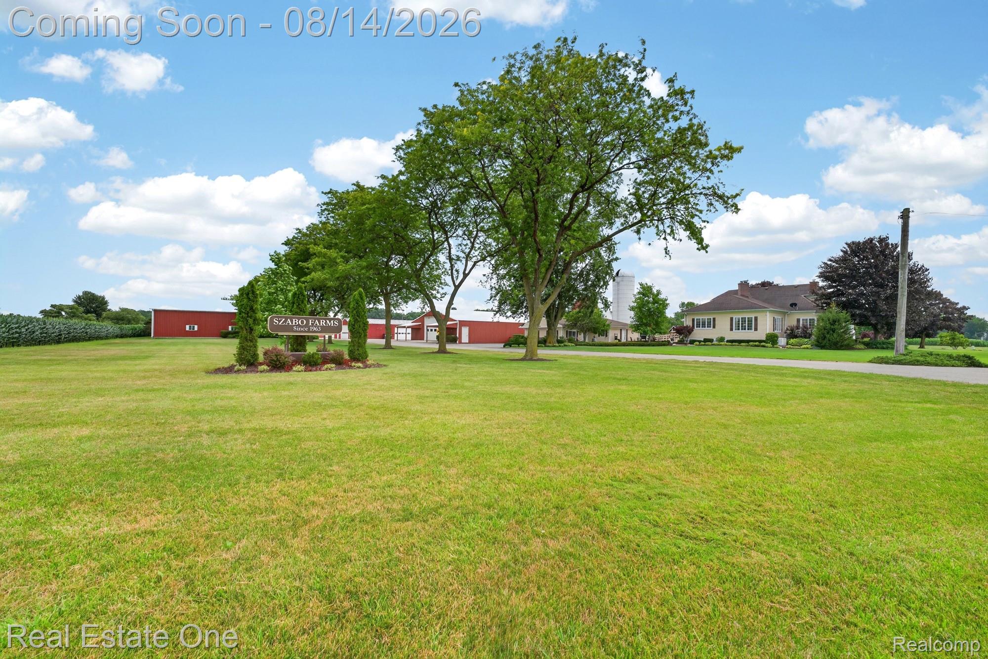 12139 Gooding Road Milan, MI 48160 - Photo 3 of 98 Expansive green lawn, mature trees, white silo, red outbuildings, and a residential structure with a light-colored exterior