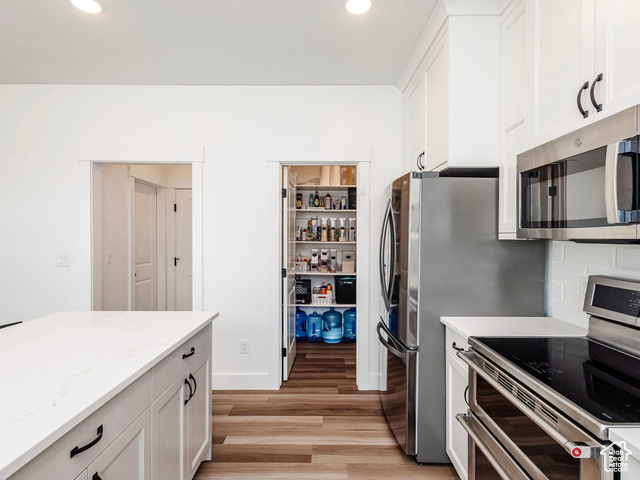 374 Ropelato Drive Nibley, UT 84321 - Photo 4 of 15 Kitchen with stainless steel appliances, light wood finished floors, white cabinets, recessed lighting, and light stone counters