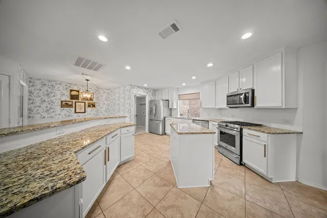 a large kitchen with stainless steel appliances kitchen island granite countertop a sink and cabinets