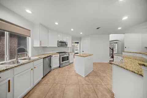 a large kitchen with kitchen island a sink dishwasher a stove and a refrigerator with wooden floor