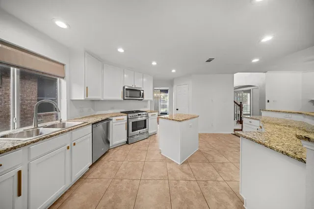 a large kitchen with kitchen island a sink dishwasher a stove and a refrigerator with wooden floor