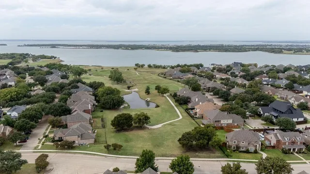 an aerial view of ocean with residential house with outdoor space and trees around