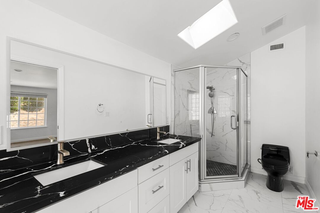 18657 Kirkcolm Lane Porter Ranch, CA 91326 - Photo 16 of 22 a bathroom with a granite countertop sink a toilet a mirror and shower