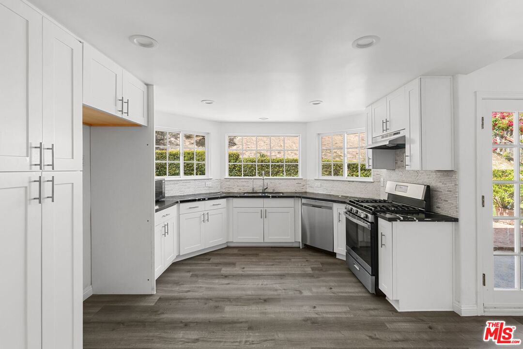 18657 Kirkcolm Lane Porter Ranch, CA 91326 - Photo 6 of 22 a kitchen with granite countertop a stove top oven sink and cabinets