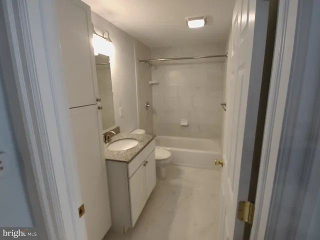 a bathroom with a granite countertop sink a toilet and shower