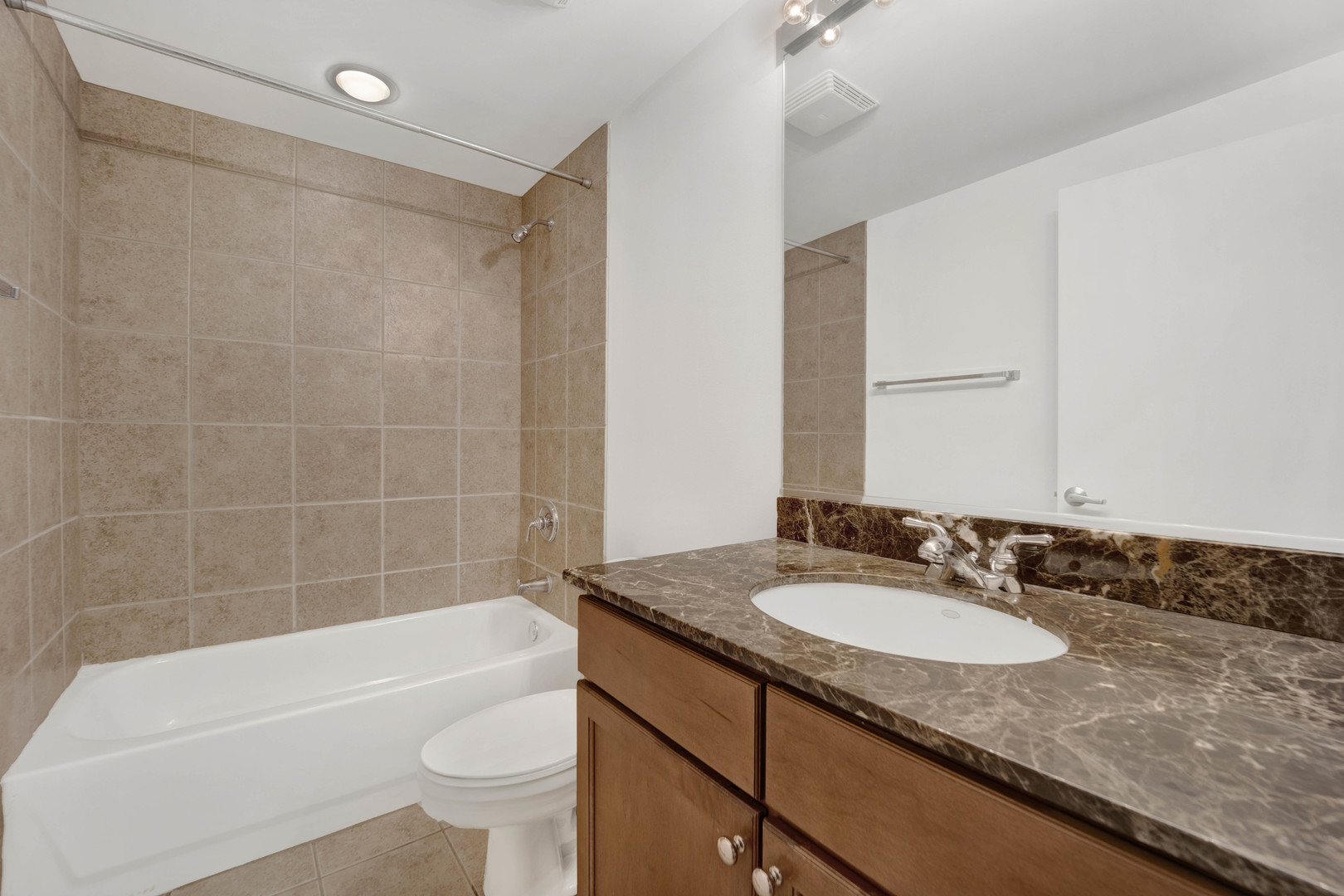 1070 West 15th Street, Unit 112 Chicago, IL 60608 - Photo 14 of 29 a bathroom with a granite countertop sink a toilet a mirror a bathtub and shower