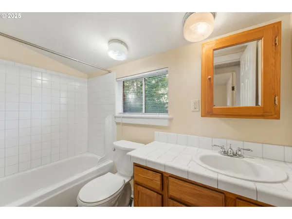 a bathroom with a granite countertop sink toilet a mirror and shower
