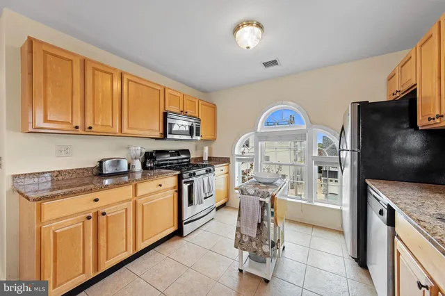 a kitchen with stainless steel appliances granite countertop a stove top oven a sink a counter space and cabinets