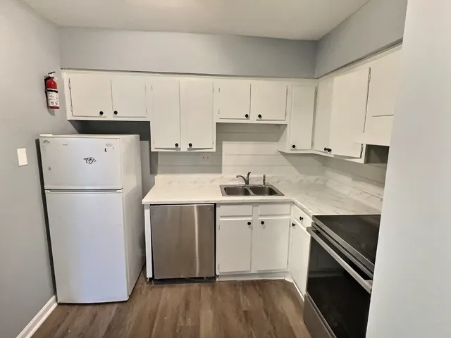a kitchen with a sink cabinets stainless steel appliances and wooden floor