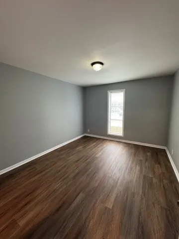 a view of empty room with window and wooden floor