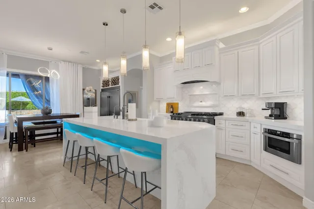 a kitchen with stainless steel appliances a stove a sink a dining table and chairs